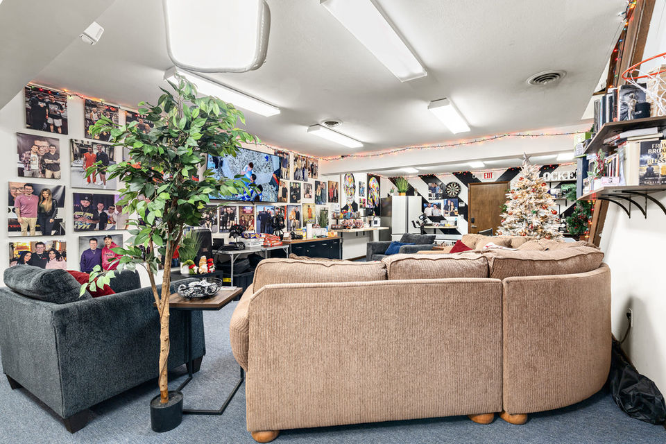 View of the podcast seating area against the black acoustic wall featuring framed motivational posters and production equipment.