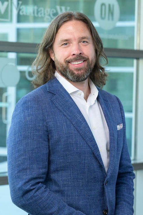 professionally dressed man with long brown hair and a greying beard