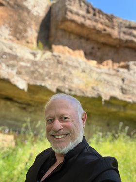 Neil Laird standing in front of sandstone cliffs.