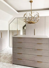 Bespoke dressing room with a central drawer island, mirrored wardrobes and gold chandelier at Highbank, Alderley Edge