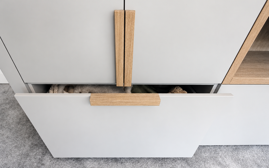 Grey playroom cabinetry with oak handles and an open storage drawer.
