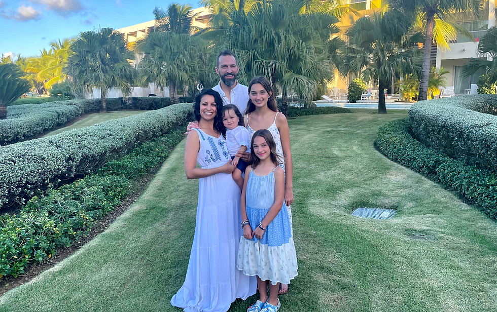 Dr. Meghna Mahambrey and Sir Andy Kuss standing with their children in a tropical resort garden, symbolizing family connectio