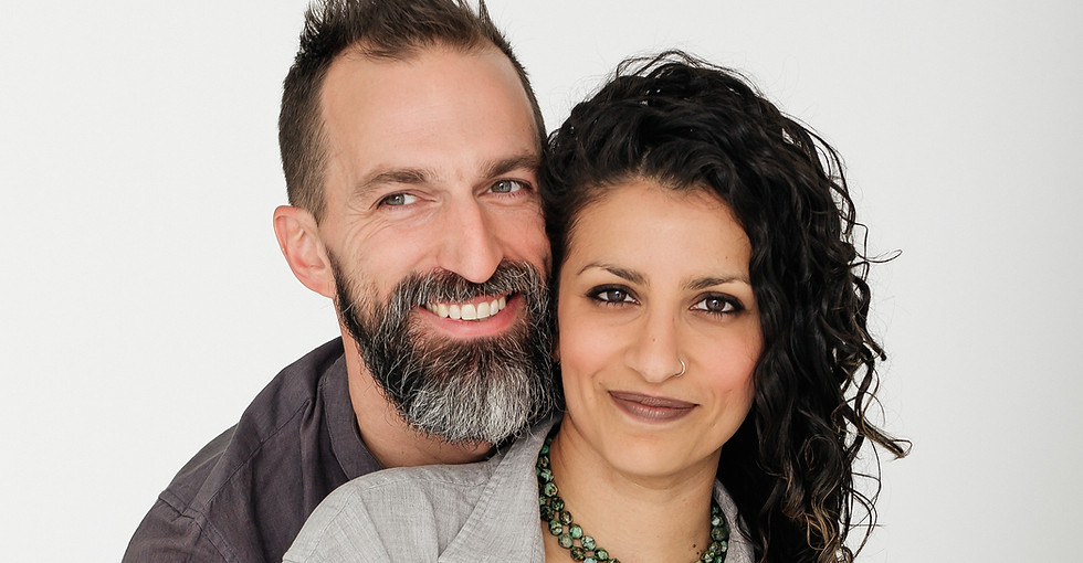 Dr. Meghna Mahambrey sitting on Sir Andy Kuss’s lap with their hands intertwined, smiling warmly in a modern studio portrait