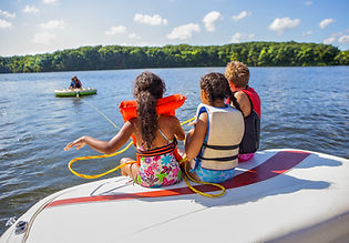 Youth on the back of the boat tubing on a Lake