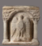 A carved marble wellhead with a large eagle centered inside an arched-frame supported by two columns.