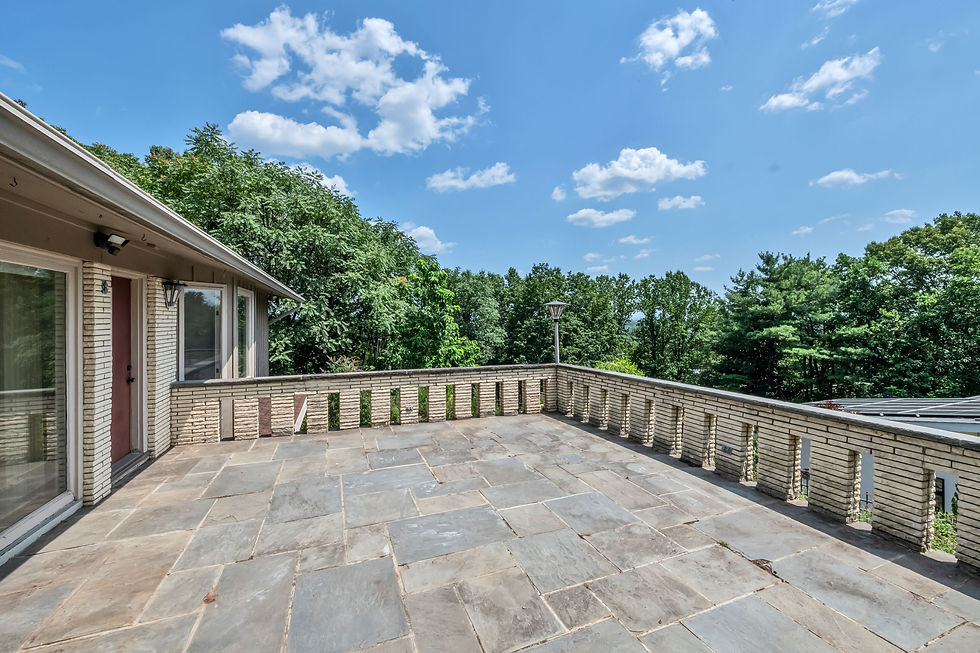 Elevated stone patio with brick railing at a mid-century modern home in Hawthorne NJ, offering serene NYC skyline views and lush greenery—ideal for outdoor entertaining. Listed by The Gill Group, top real estate team in Northen New Jersey.