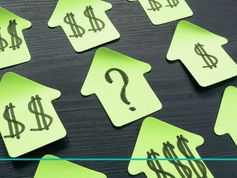 Green house-shaped paper cutouts on a dark surface, each with dollar signs, except one with a question mark, symbolizing financial uncertainty.