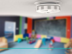 Smoke detector installed on ceiling in a brightly colored classroom, highlighting fire safety and prevention awareness.