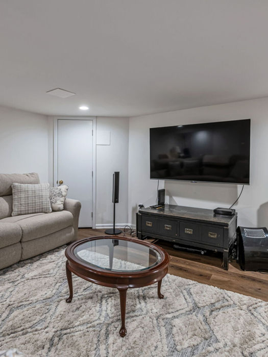 Spacious finished basement with media area, sectional sofa, and hardwood floors—ideal recreation space in this Harrington Park rental property.