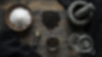 Salt in a bowl, black salt on a rustic wooden table with a mortar, jar, and glass bottle. Black cloth adds contrast.