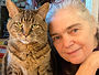 The writer Cynthia Hardy with white hair and light skin, next to a large brown tabby cat.