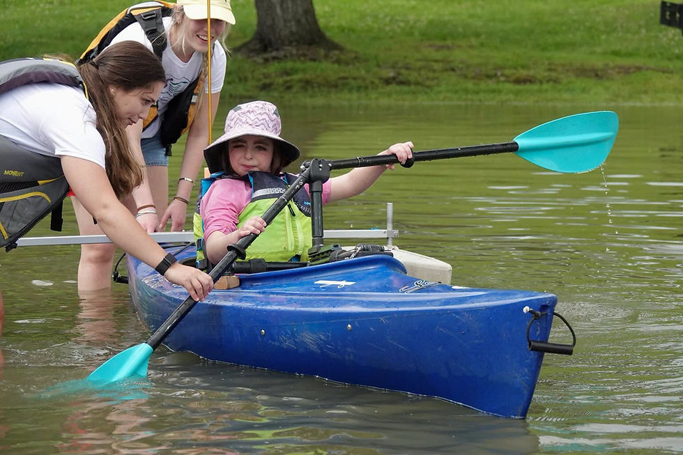 young girl with visual impairment learning to kayak using an angled Versa Paddle with guidance from an instructor