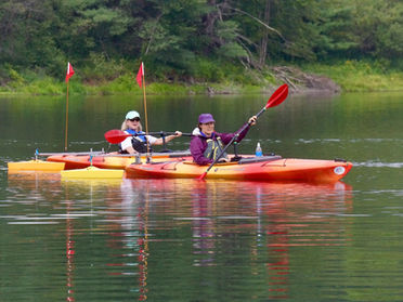 two women using adaptive kayak paddles by angle oar on a pond
