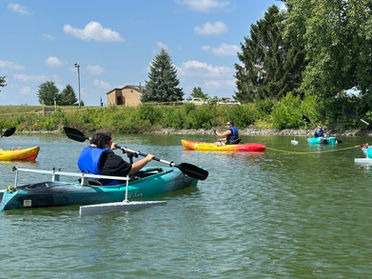 people in adapted kayaks paddling near a shoreline