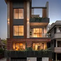 Front elevation of a modern luxury residence in New Delhi featuring a facade of grey stone cladding, vertical wooden louvers,
