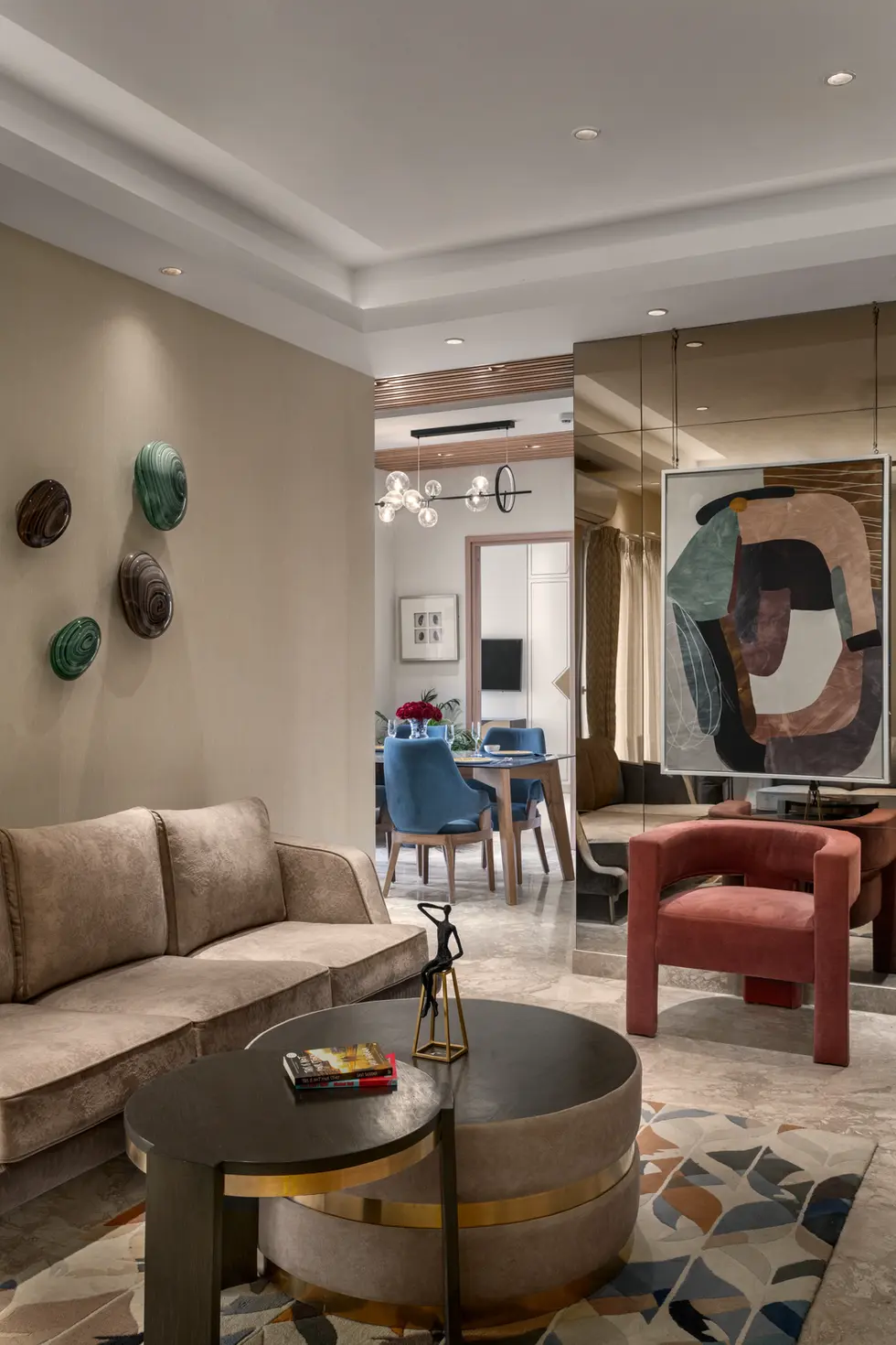 Contemporary living room in New Delhi featuring beige velvet seating, abstract ceramic wall art, and a decorative mirrored co