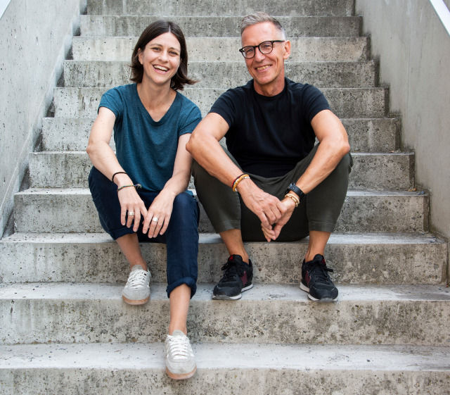Zwei Business-Coaches von SOULWORXX - Sarah Buser und Markus Müller - sitzen lächelnd auf einer Betontreppe – Team für Future Skills, Innovation und Change Management in der Schweiz.
