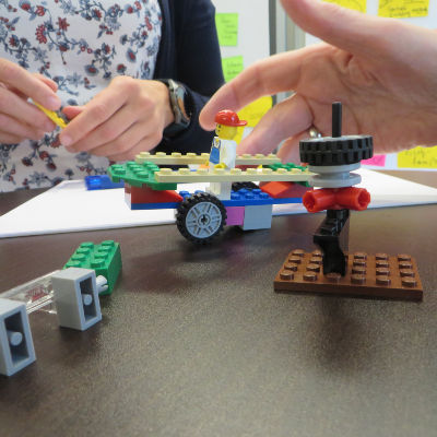 Hände, die Legobausteinen metaphorisch etwas nachbauen