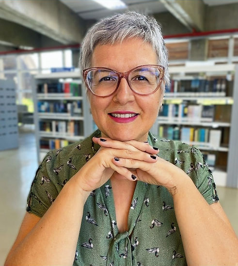 Psicóloga Valéria Gallo: mulher branca de óculos, cabelos curtos e grisalhos, olha a frente e sorri com as mãos no queixo.