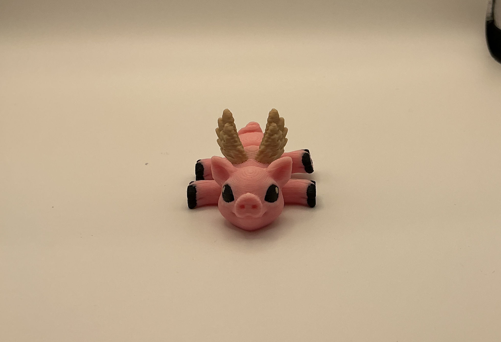 Pink articulated flying pig 3D printed mini with wings on a white background
