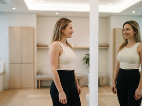 American woman reviewing her body contouring results in a modern Seoul clinic mirror, soft clinical lighting, confident expression