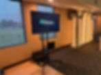 TV display on rolling stand with Aurora Audio Visual logo at indoor event venue.