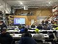Safety training session with projection screen and seating inside an industrial warehouse.