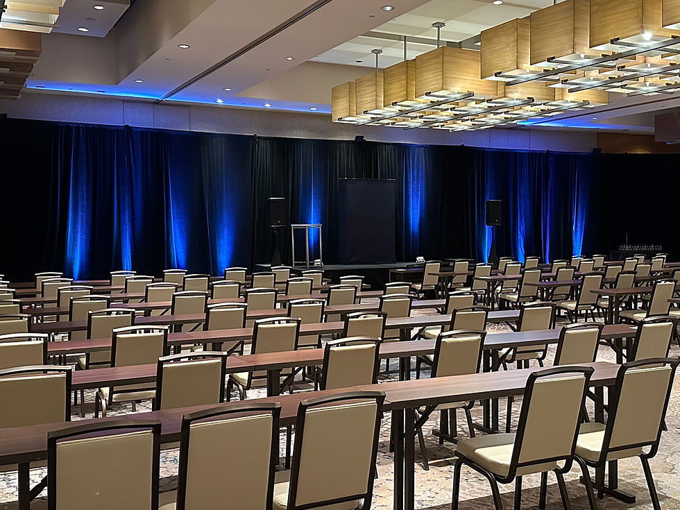 Blue uplighting on draped stage backdrop for corporate conference setup.