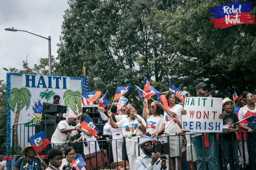 Community members waving Haitian flags and holding signs at a Relief for Haiti gathering