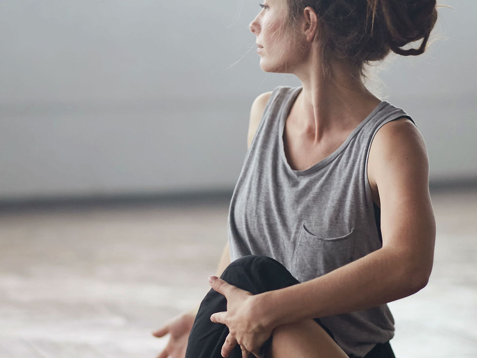 Kvinde der strækker ud ved at tviste sin torso og bøje sit ene ben over det andet.
