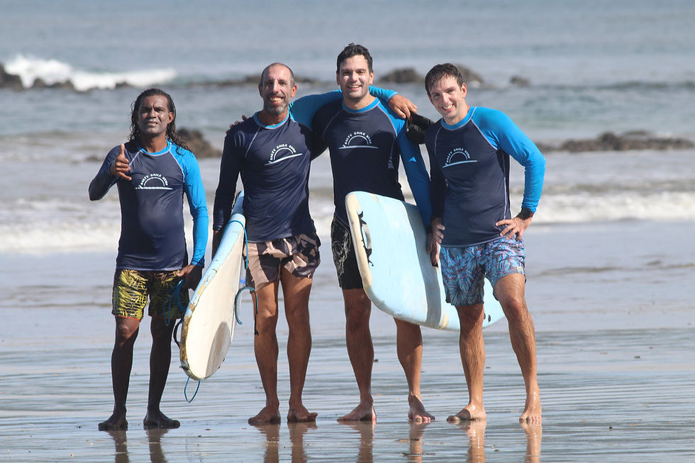 Surf instructors from Salty Smile Surf School standing with surfboards on Tamarindo beach in Costa Rica
