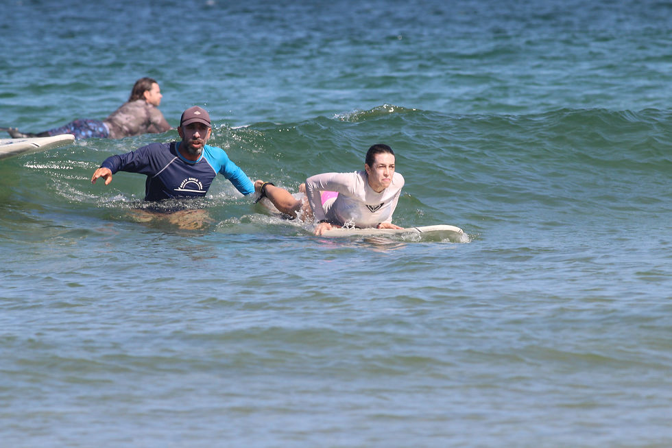 Surf instructor helping a beginner catch a wave during a lesson in Tamarindo Costa Rica