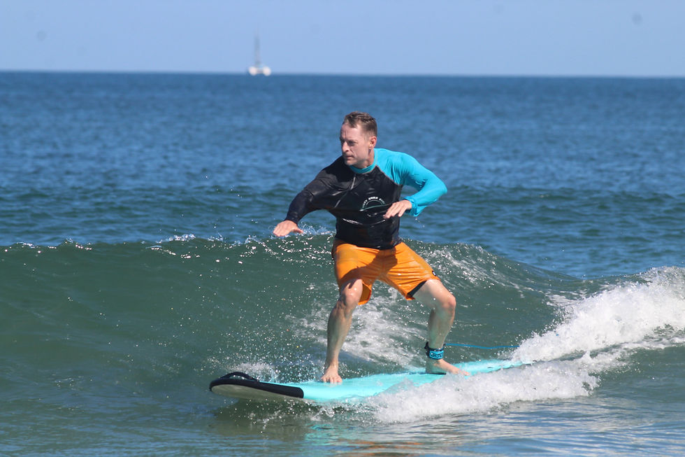 Beginner surfer riding a small green wave independently after three surf lessons in Tamarindo, Costa Rica.