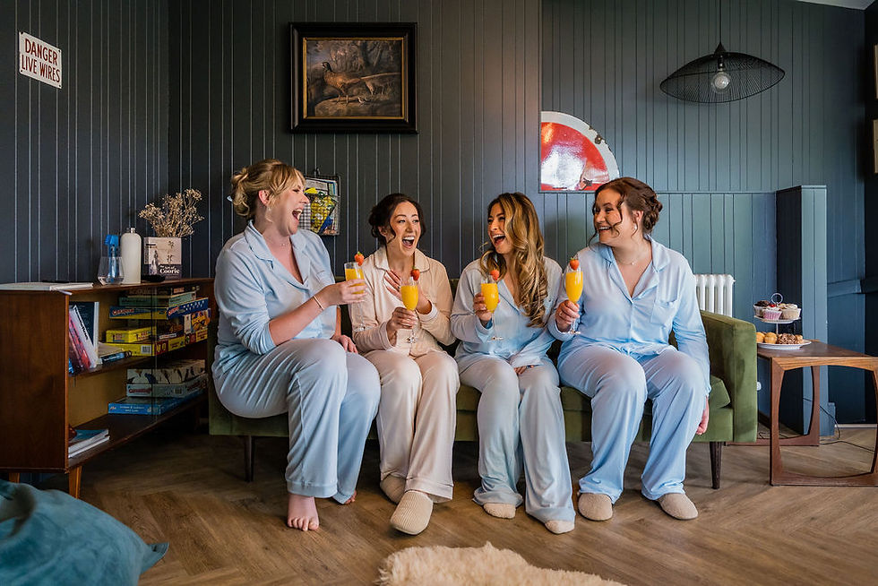 Bride and bridesmaids laughing and sharing a toast before wedding ceremony at Venachar Lochside