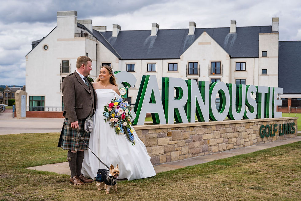 Wedding couple posing with Carnoustie sign and Golf Hotel and Spa in the background on Angus coast