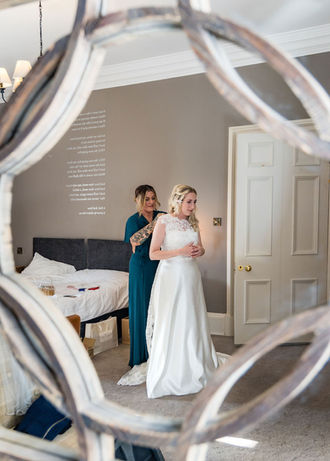 Bride getting ready for her big day with the help of her bridesmaid.