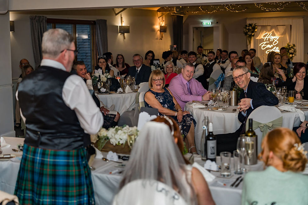 Guests laughing together during speeches at a winter wedding at Forbes of Kingennie near Dundee, Scotland.
