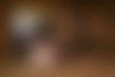 The groom relaxes on a cozy couch by the fireplace, while his bride rests peacefully on his lap, creating a picture of contentment and newlywed bliss.