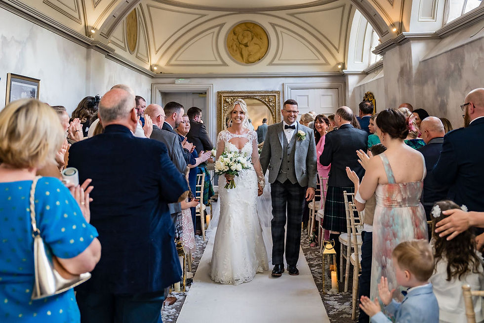 Newlyweds walking out of ceremony at Balbirnie House surrounded by cheers from family and friends