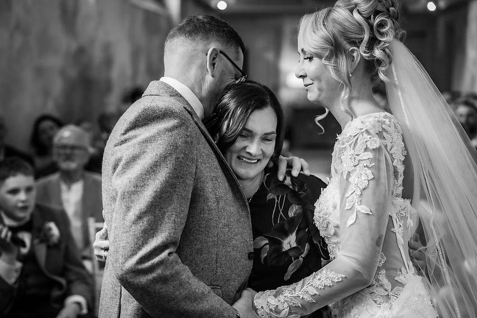 Newlyweds sharing an emotional hug with their surprised wedding witness during the ceremony at Balbirnie House.