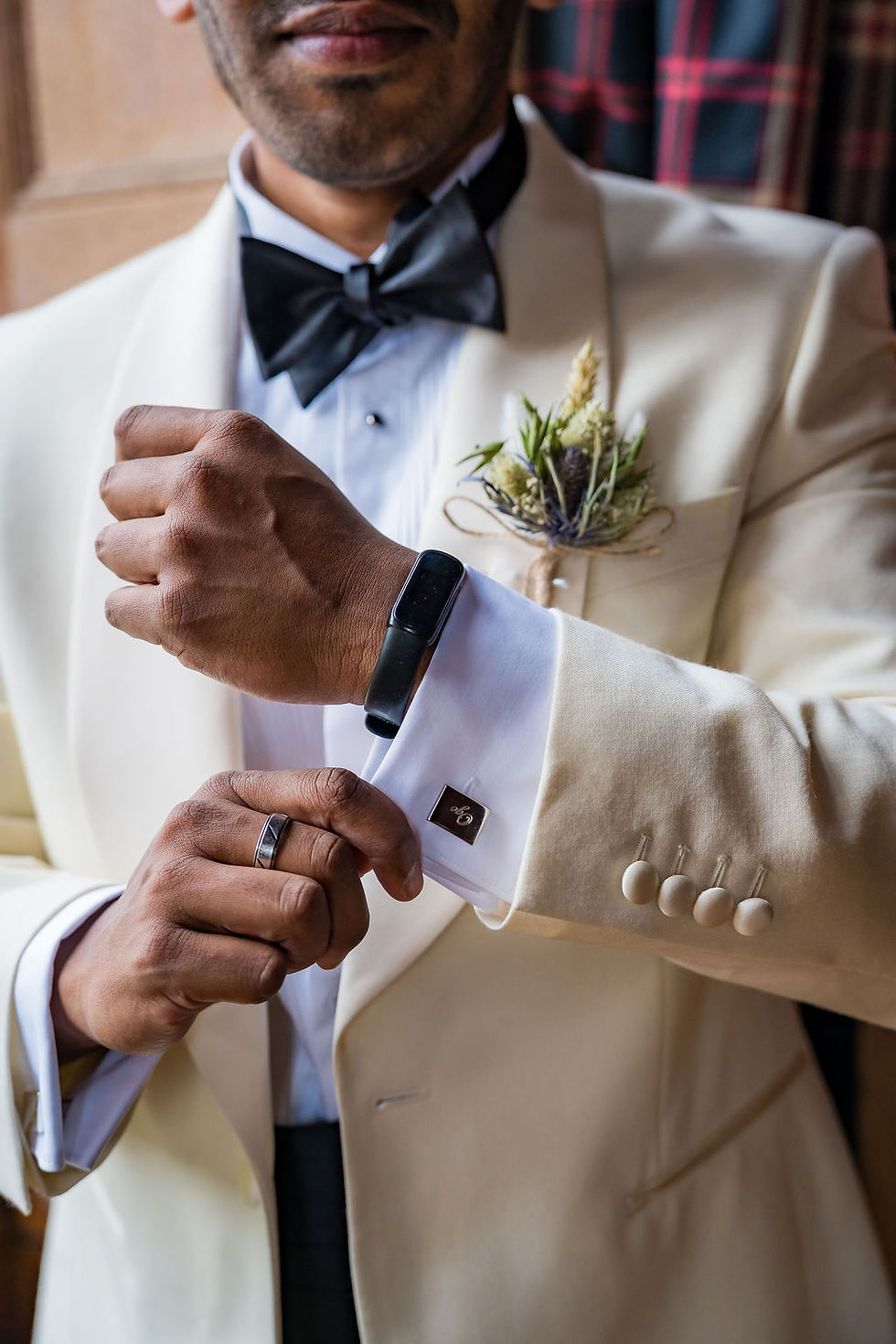A close-up shot of the groom's hands fastening his cufflinks during a quiet moment before the wedding.