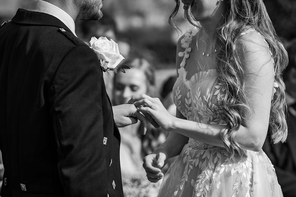 ride and groom exchanging wedding rings during their outdoor ceremony at Balbirnie House in Fife, photographed in a relaxed and candid documentary style.
