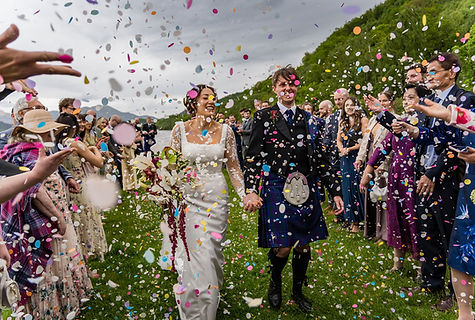 Newlyweds celebrating with raised hands during a confetti moment at Venachar Lochside wedding venue