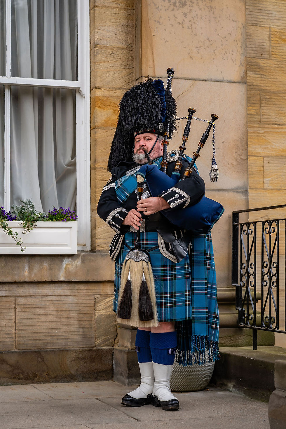 Scottish piper performing outside Balbirnie House before the wedding ceremony, welcoming arriving guests.
