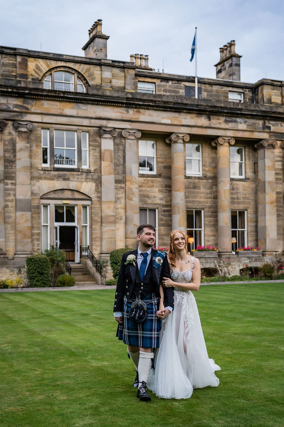 Bride and groom walking hand in hand with Balbirnie House in the background, captured by Balbirnie House wedding photographer ZibiZ Photo in a relaxed, romantic, and candid style.