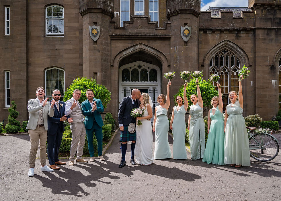 Bridal party cheering as the newlyweds kiss during a celebratory moment at Drumtochty Castle in Aberdeenshire