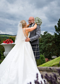 Newlyweds share a joyful moment on Peebles Hydro’s lush lawns, surrounded by breathtaking mountain views—natural and timeless Scottish wedding photography.