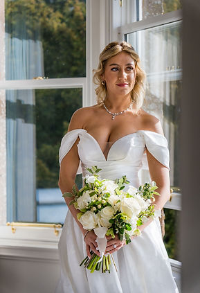 Bride ready for her wedding, standing by the window at Kinclune House, captured in soft natural light.