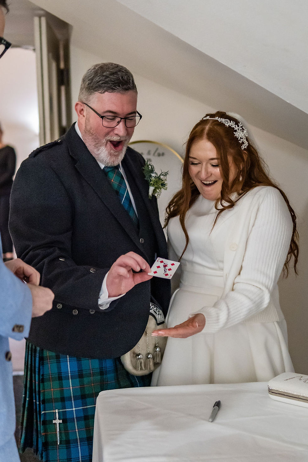 Magician performing a close-up card trick for the bride and groom during the wedding reception at Forbes of Kingennie near Dundee, Scotland.