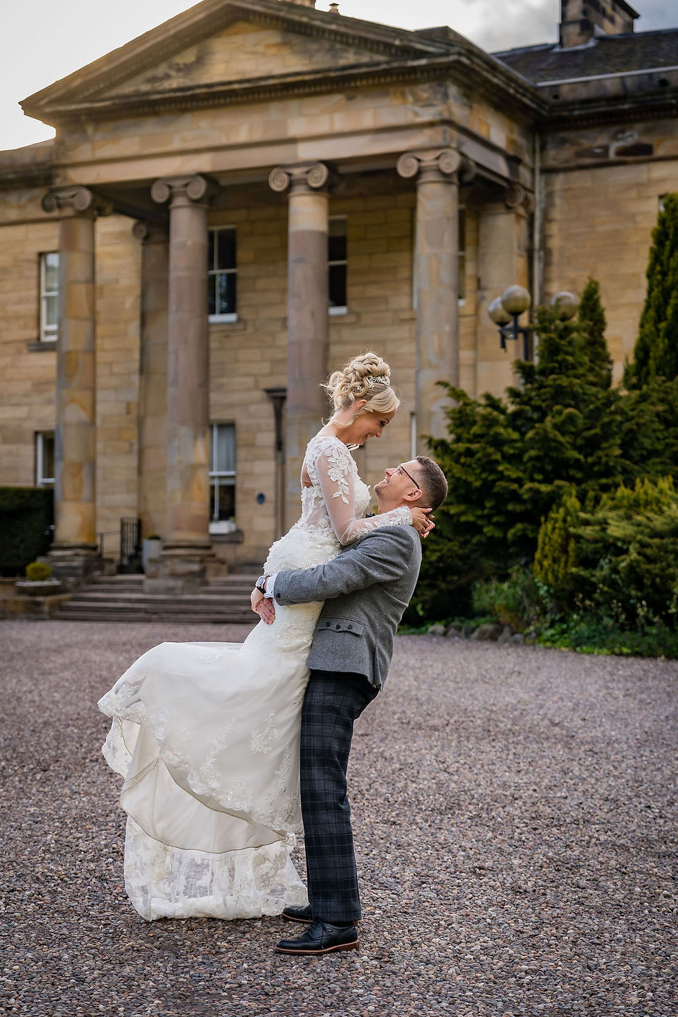 Groom lifting bride outside Balbirnie House during relaxed and playful wedding portraits in Scotland